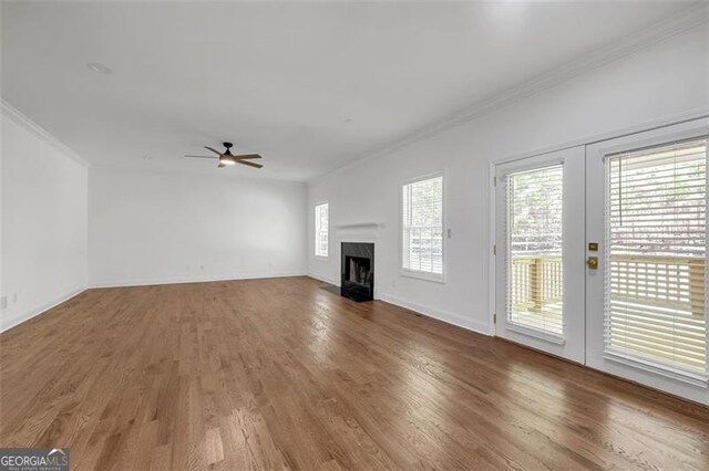 unfurnished living room featuring ornamental molding, a ceiling fan, wood finished floors, and a premium fireplace