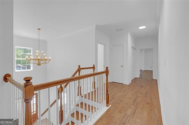 hallway with crown molding, light wood-style floors, a chandelier, baseboards, and an upstairs landing
