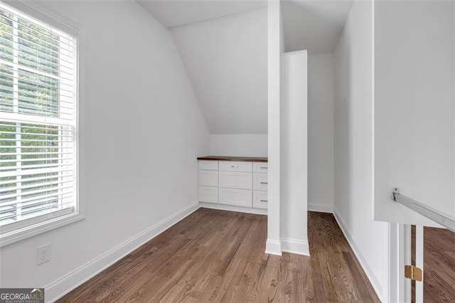interior space featuring baseboards, wood finished floors, and lofted ceiling
