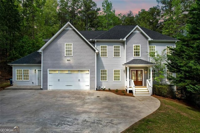 colonial house featuring an attached garage, driveway, and french doors