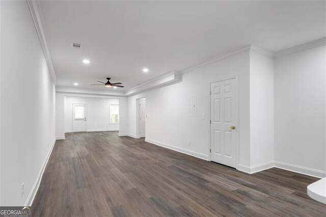 unfurnished living room featuring a ceiling fan, ornamental molding, and dark wood-type flooring