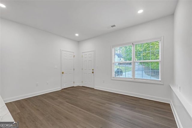 spare room with recessed lighting, baseboards, visible vents, and dark wood-type flooring
