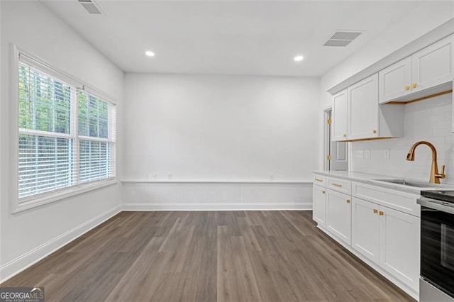 kitchen with a sink, light countertops, dark wood finished floors, white cabinetry, and visible vents