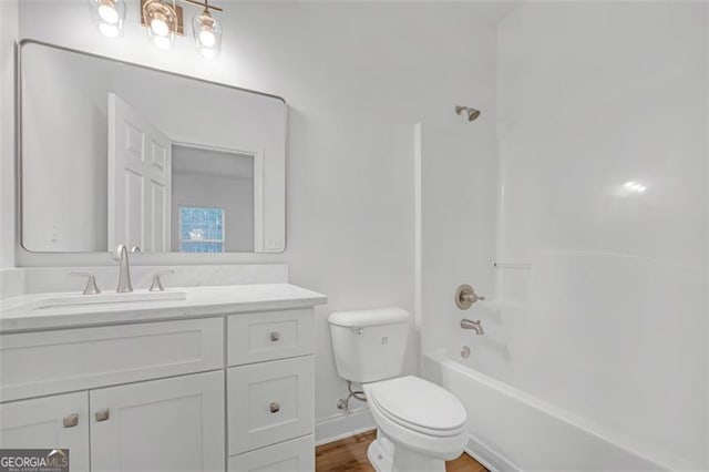 bathroom featuring vanity, toilet, wood finished floors, and shower / washtub combination