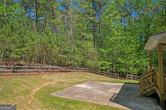 view of yard featuring a patio, a view of trees, and a fenced backyard