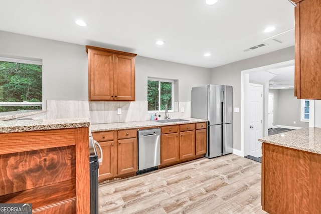 kitchen with light stone counters, a sink, appliances with stainless steel finishes, visible vents, and light wood-type flooring