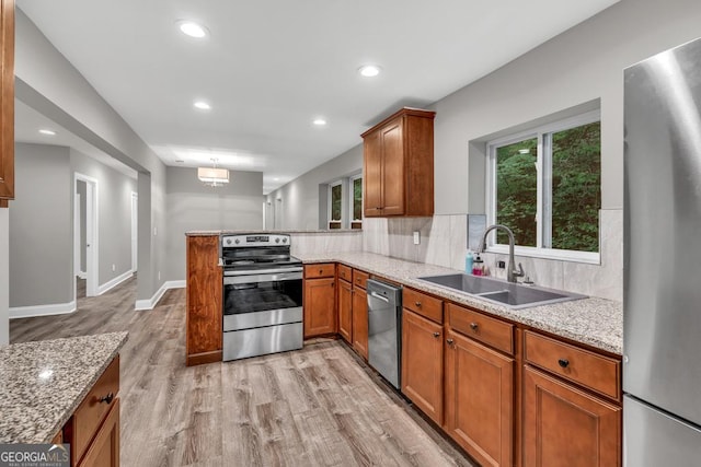 kitchen featuring decorative backsplash, a sink, light wood-style floors, stainless steel appliances, and brown cabinetry