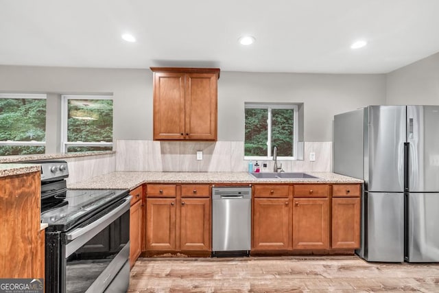 kitchen with light stone countertops, stainless steel appliances, a wealth of natural light, and a sink