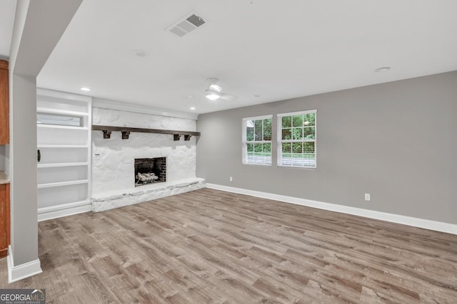 unfurnished living room with a fireplace, wood finished floors, visible vents, and baseboards