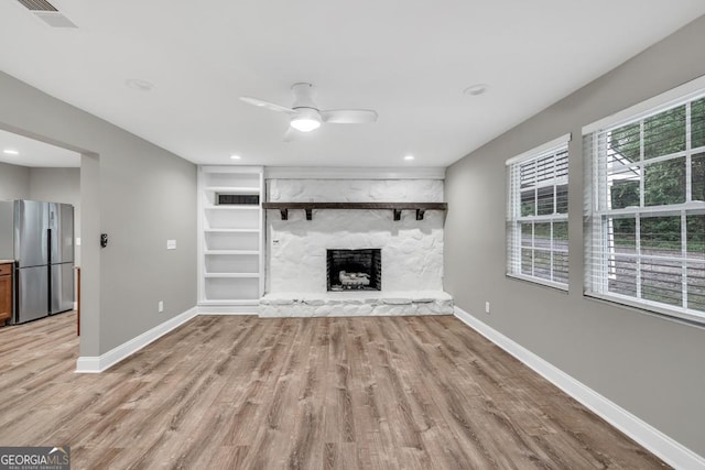 unfurnished living room with baseboards, visible vents, light wood-type flooring, and a fireplace