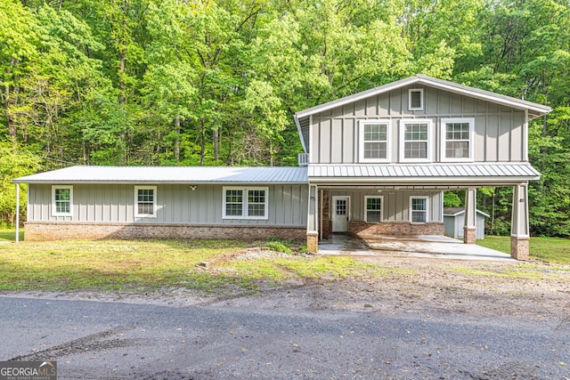 traditional home featuring a porch, metal roof, a carport, board and batten siding, and brick siding