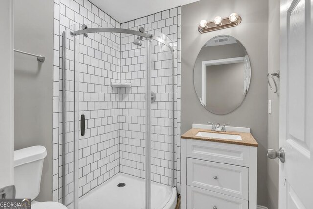 bathroom with a stall shower, toilet, and vanity