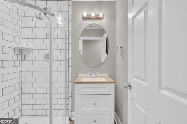 bathroom with a tile shower and vanity