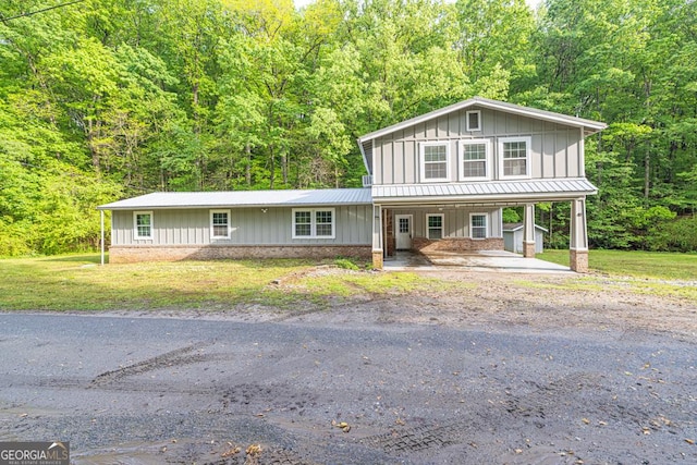 view of front facade featuring covered porch, board and batten siding, a carport, and a front lawn