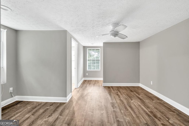 spare room with a textured ceiling, ceiling fan, wood finished floors, and baseboards