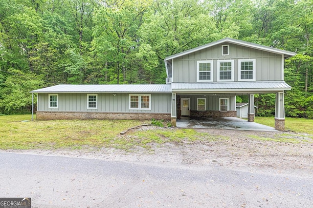 view of front of property featuring driveway, board and batten siding, metal roof, a porch, and a view of trees