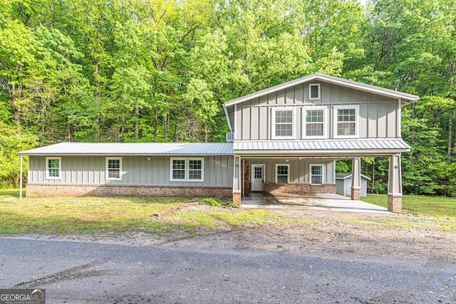 view of front facade featuring board and batten siding, a porch, brick siding, metal roof, and a carport