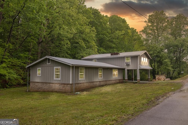 view of front of property featuring board and batten siding, a front yard, brick siding, and metal roof