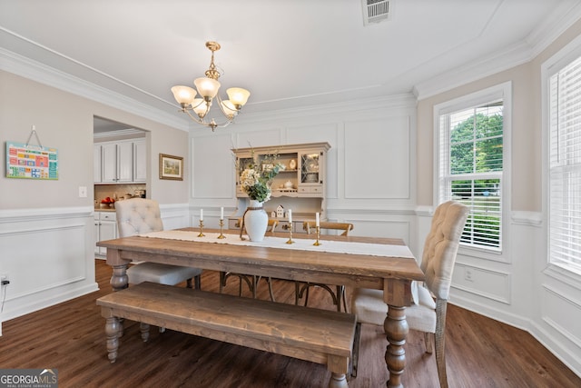 dining space featuring an inviting chandelier, wood finished floors, visible vents, a decorative wall, and crown molding