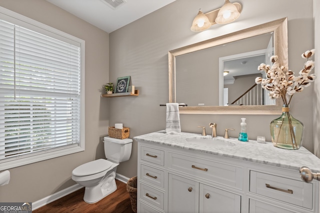bathroom featuring toilet, visible vents, baseboards, wood finished floors, and vanity
