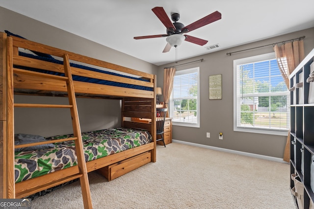 carpeted bedroom with visible vents, a ceiling fan, and baseboards