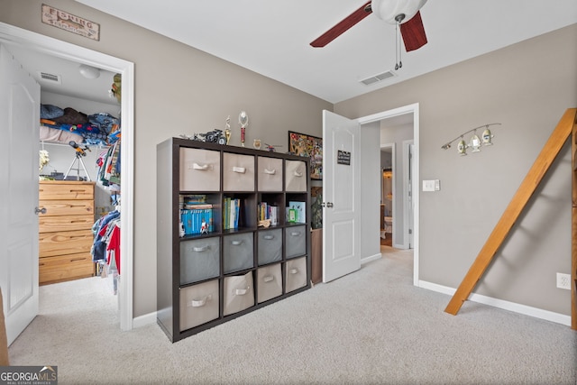 interior space with baseboards, a ceiling fan, visible vents, and carpet
