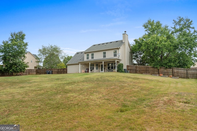rear view of property featuring a yard, a chimney, and a fenced backyard