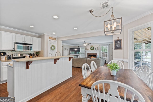 dining area with light wood finished floors, crown molding, and ceiling fan with notable chandelier