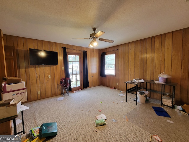 206 New Dr, Claxton, GA 30417 - unfurnished living room with carpet flooring, a ceiling fan, a textured ceiling, and wood walls