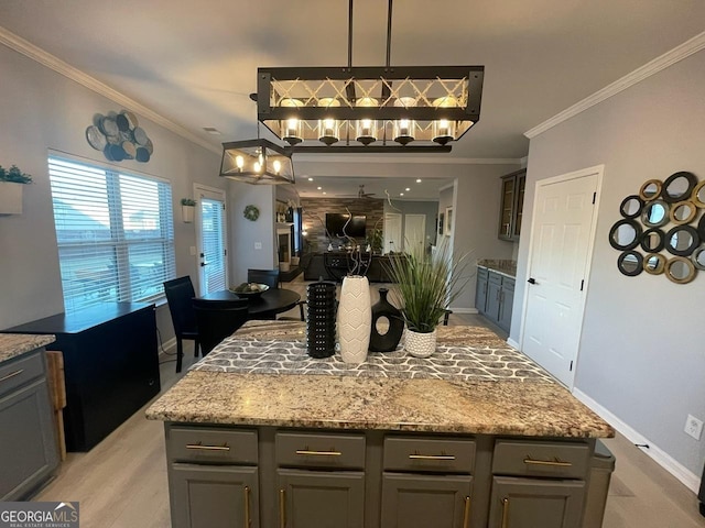 kitchen featuring crown molding, light stone counters, gray cabinets, baseboards, and open floor plan