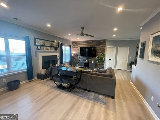 living area with ceiling fan, visible vents, a fireplace, wood finished floors, and baseboards