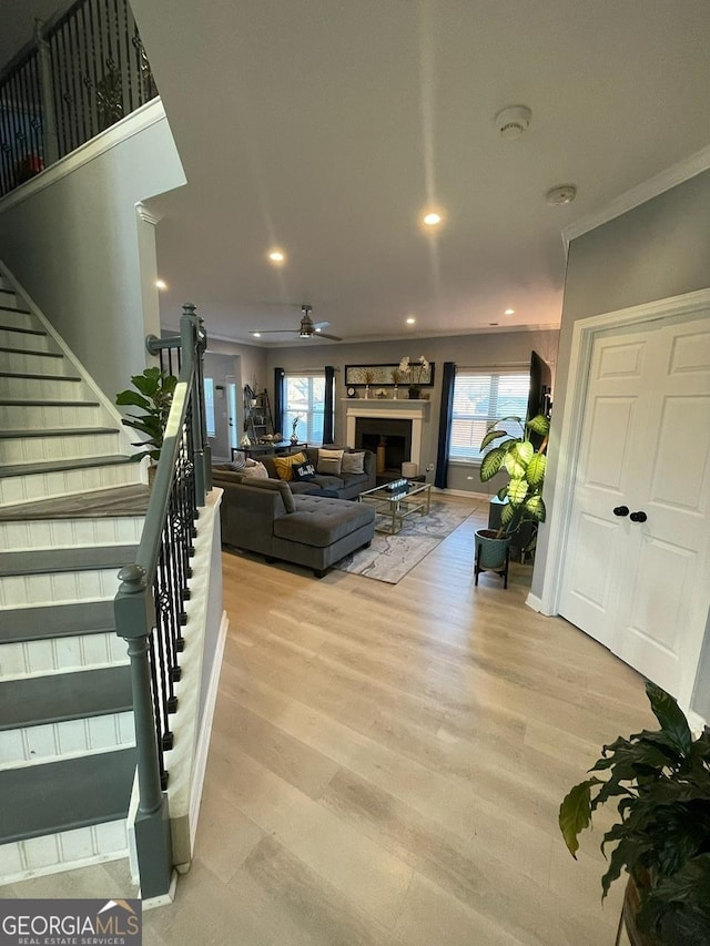 living room featuring stairs, a fireplace, ceiling fan, light wood-type flooring, and recessed lighting
