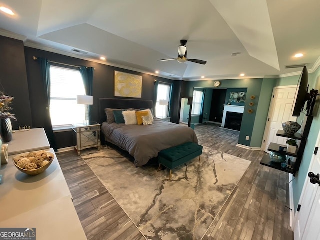 bedroom featuring visible vents, ornamental molding, a raised ceiling, and wood finished floors
