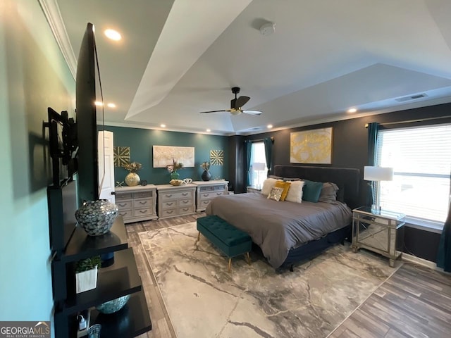 bedroom with visible vents, a raised ceiling, crown molding, and wood finished floors