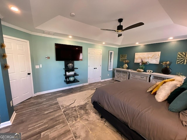 bedroom with crown molding, a raised ceiling, recessed lighting, baseboards, and wood finished floors