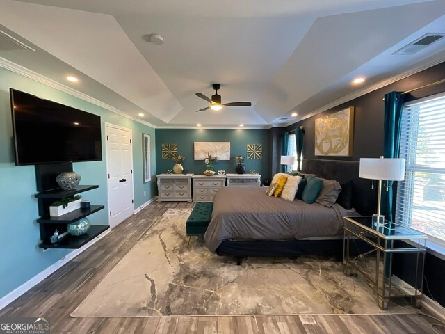 bedroom with visible vents, ornamental molding, wood finished floors, baseboards, and a raised ceiling
