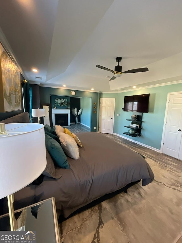 bedroom featuring recessed lighting, a ceiling fan, a raised ceiling, and a fireplace