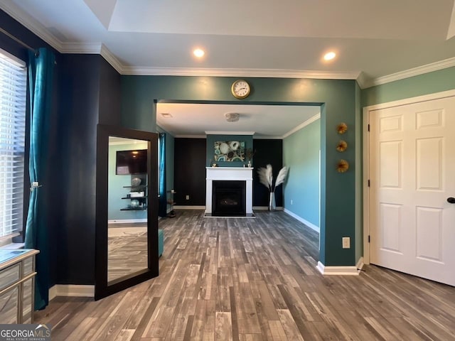 unfurnished living room with baseboards, crown molding, wood finished floors, and a fireplace