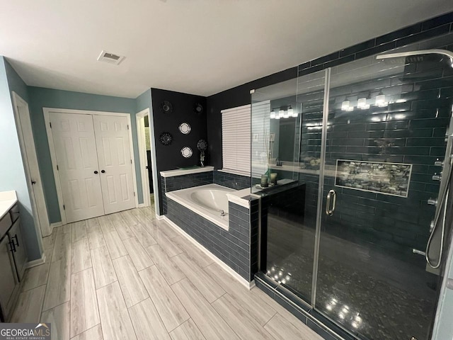 full bath with a bath, visible vents, a stall shower, wood finished floors, and vanity