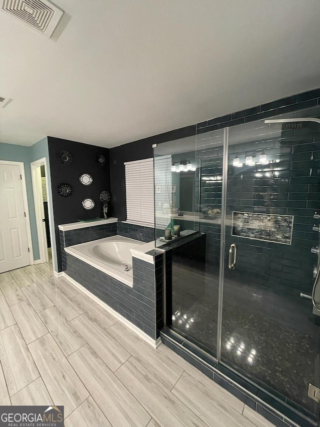 full bath with visible vents, wood tiled floor, a garden tub, and a stall shower