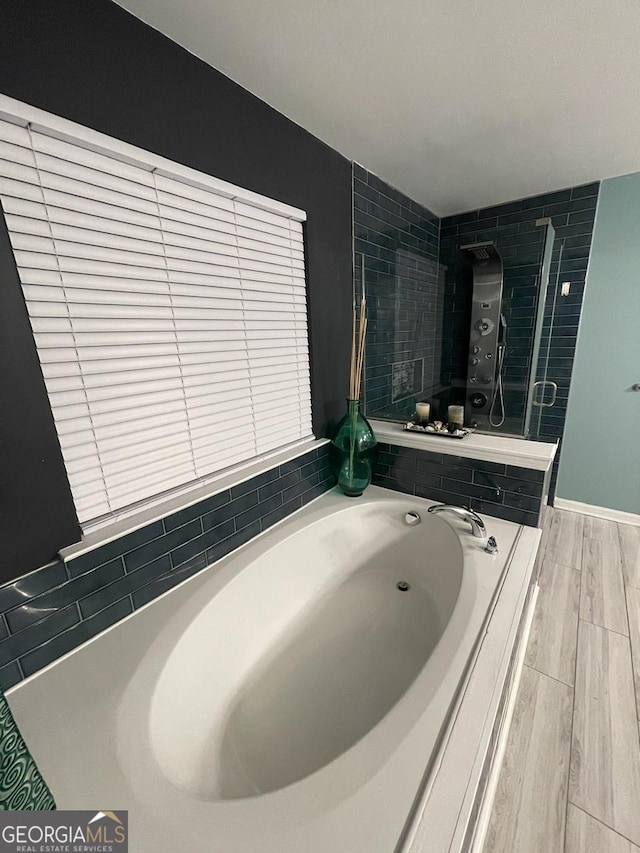 bathroom with a garden tub and wood finished floors