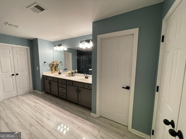 full bathroom featuring double vanity, wood tiled floor, a stall shower, and visible vents