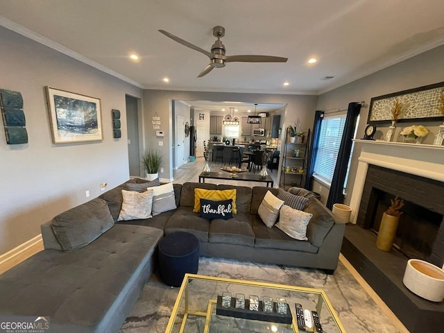 living area with crown molding, a brick fireplace, baseboards, and ceiling fan