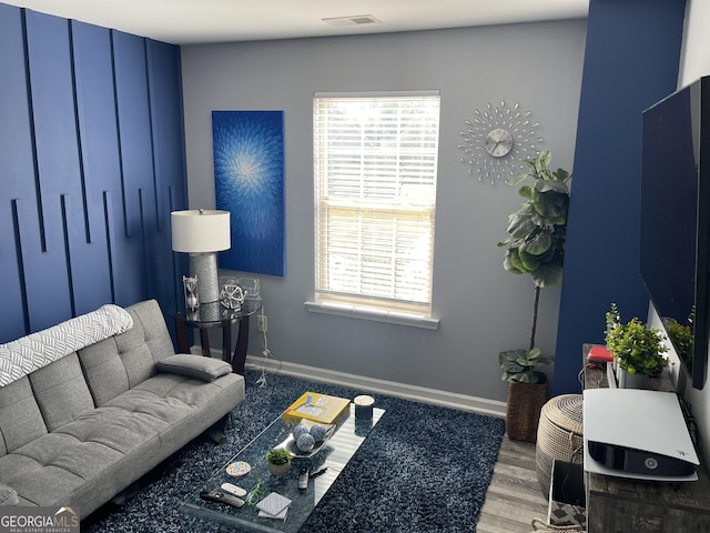 living area with visible vents, baseboards, and wood finished floors