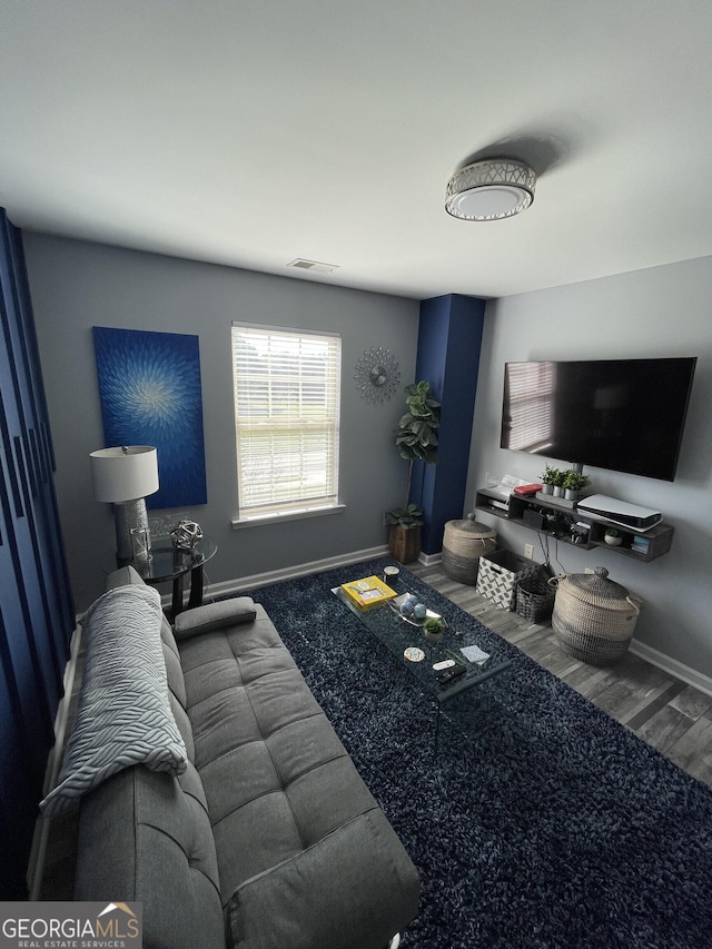 living room with visible vents, baseboards, and wood finished floors