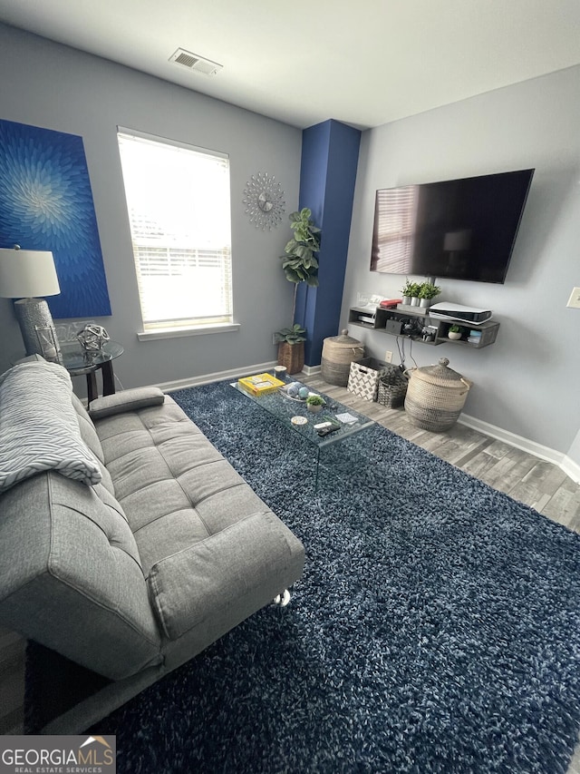 living area featuring baseboards, visible vents, and wood finished floors