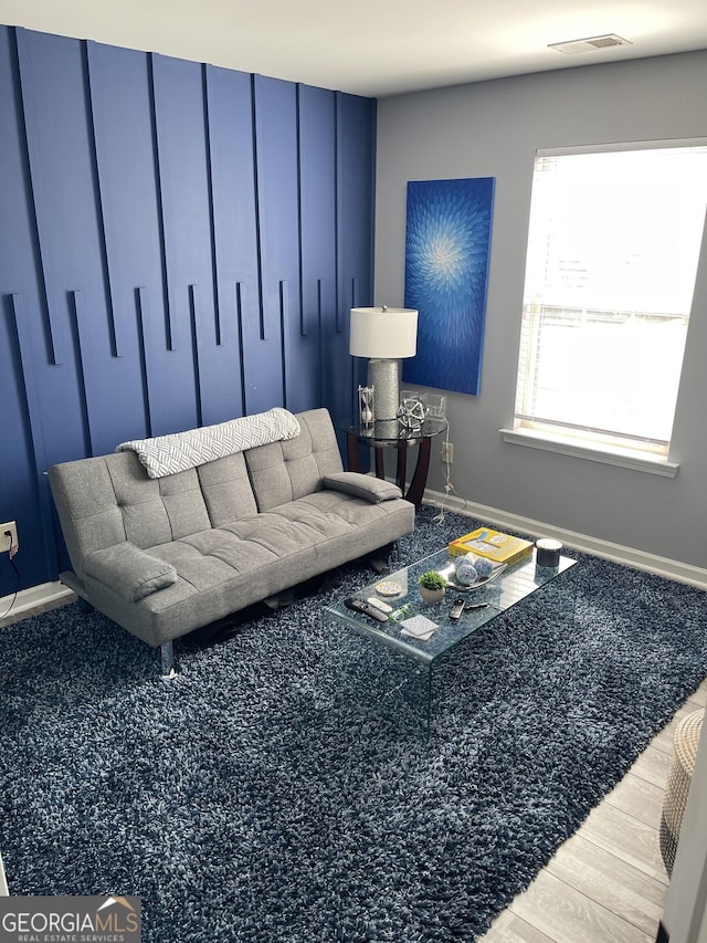living area featuring baseboards, visible vents, and wood finished floors