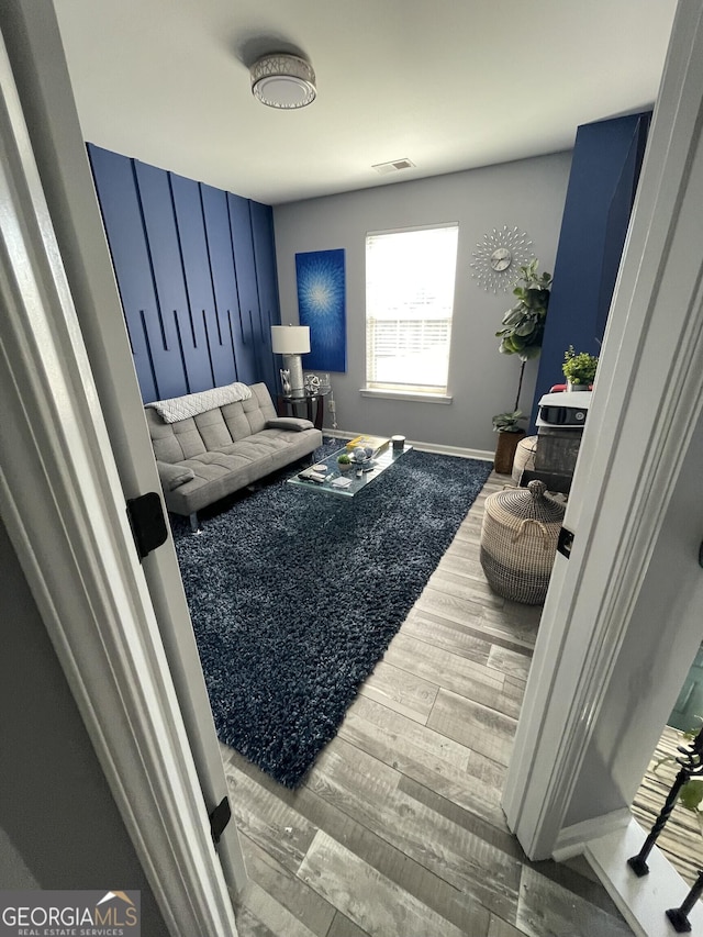 living area with visible vents, baseboards, and wood finished floors