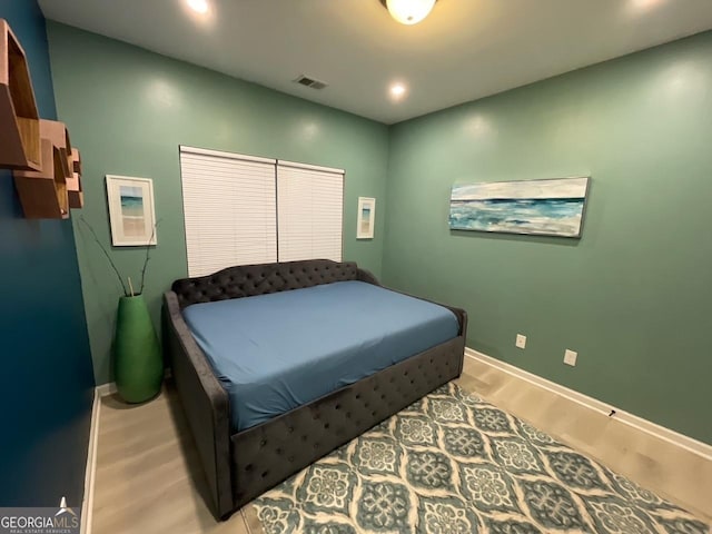 bedroom with visible vents, light wood-style flooring, and baseboards