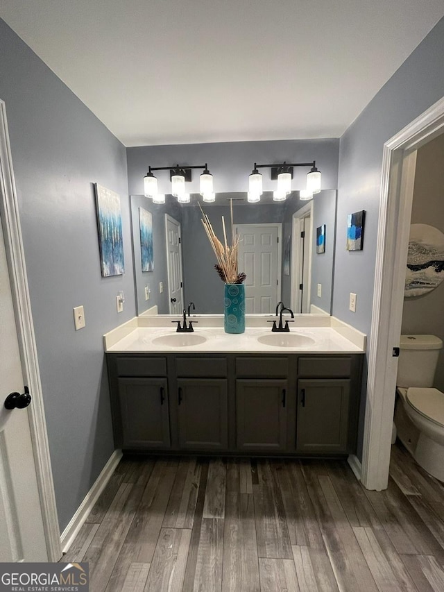 full bath featuring a sink, toilet, and wood finished floors
